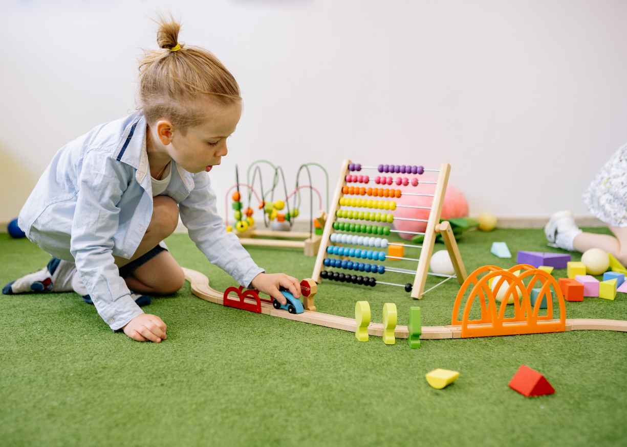 A baby crawling across a soft mat with an educator nearby at Lumora