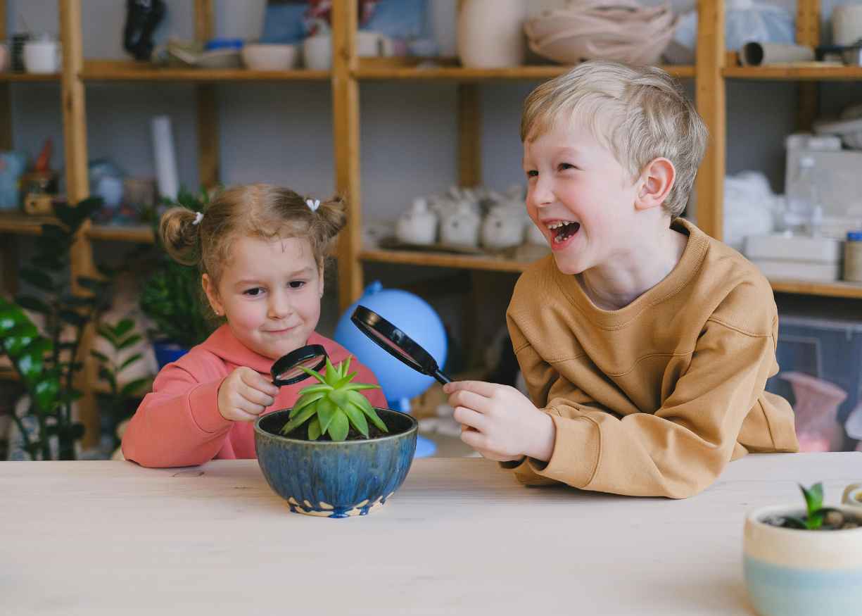 Two children exploring a plant with magnifying glasses at Lumora